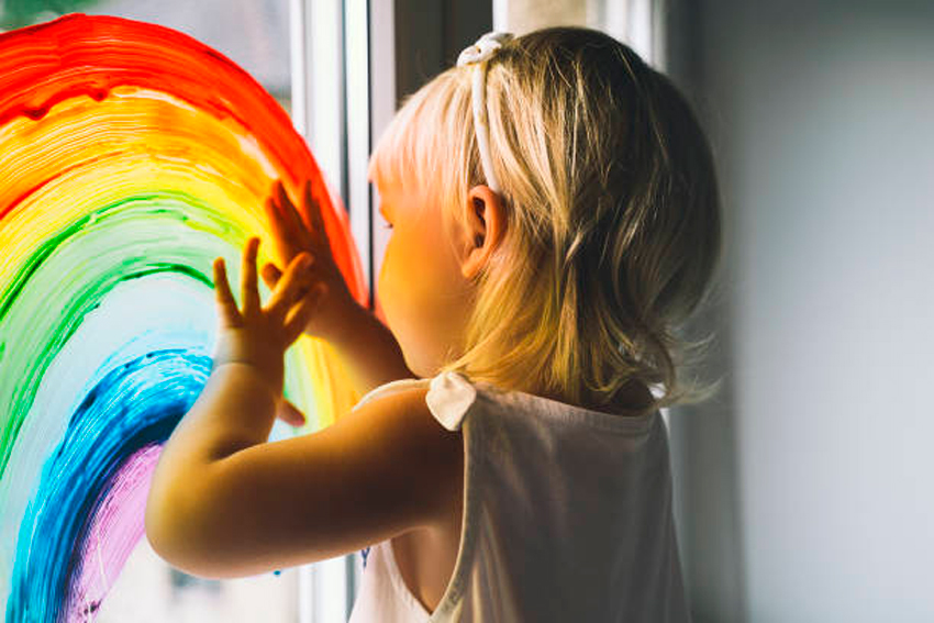 niña pintando un arcoíris en su ventana
