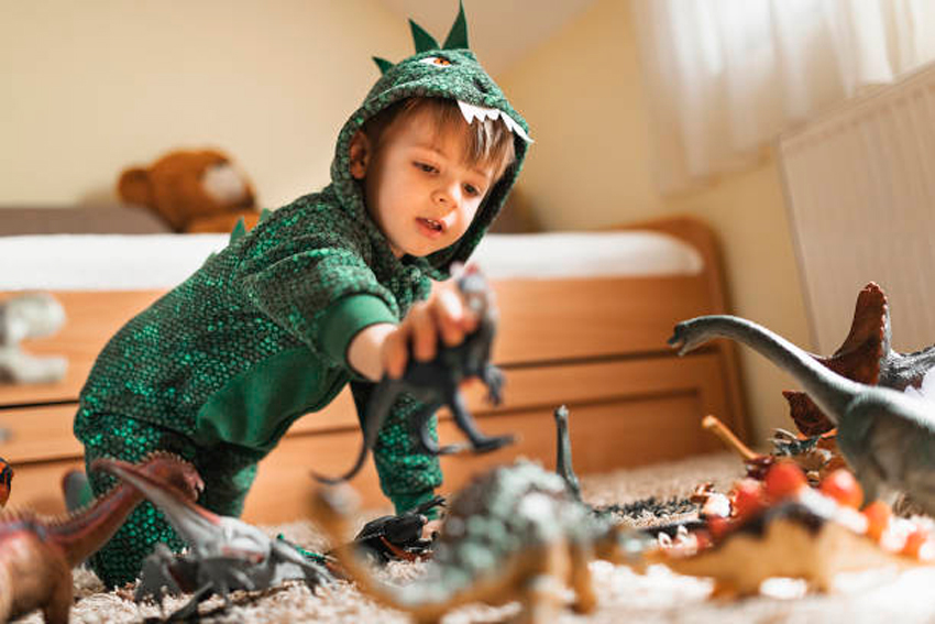 niño jugando con dinosaurios en su habitación con cama doble